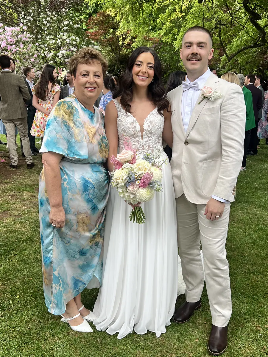 Josie with a bride and groom on a lawn among their guests