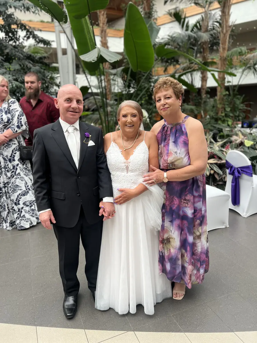 Josie with a bride and groom at an indoor reception