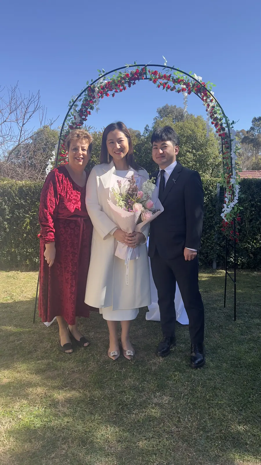 Josie with a couple beneath a rose arch in a garden